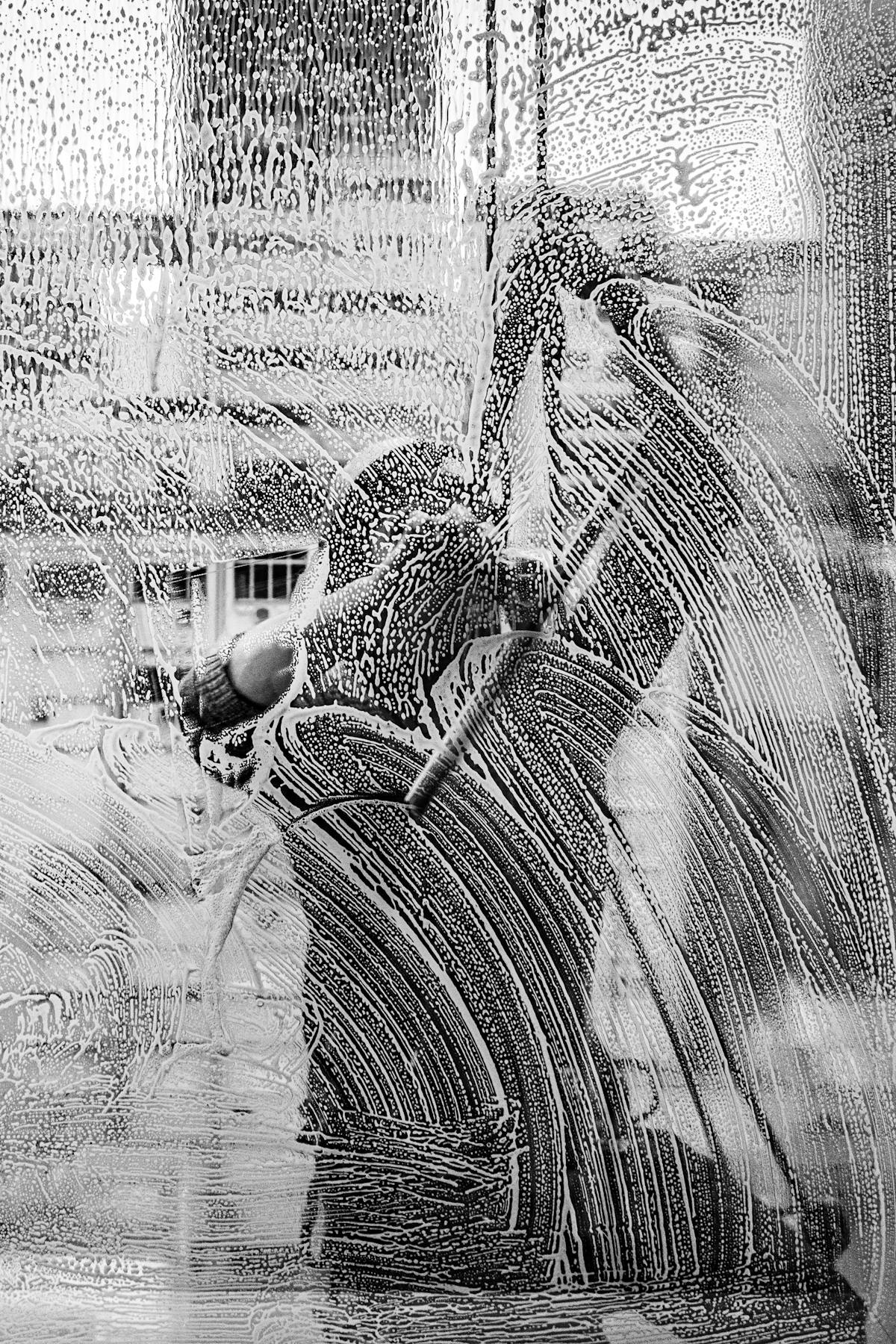 Black and white photo of a window covered in suds while being washed